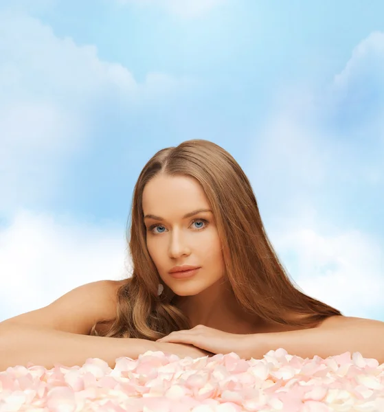 Bella donna con i capelli lunghi e petali di rosa — Foto Stock