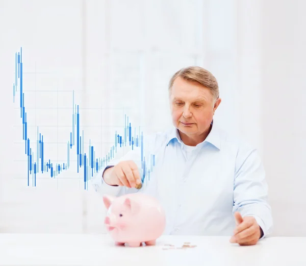 Velho colocando moeda em grande banco porquinho — Fotografia de Stock