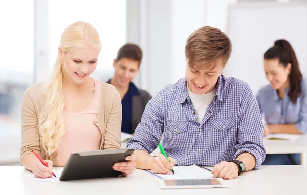 Dos estudiantes sonrientes con tablet pc y notebooks —  Fotos de Stock