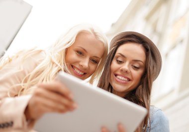 Two beautiful girls looking into tablet pc clipart