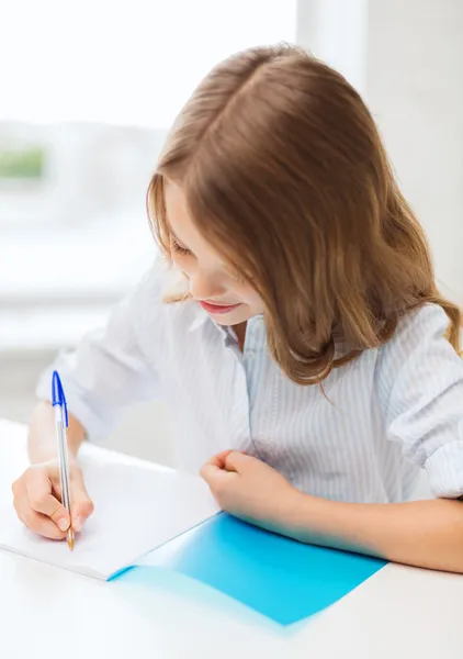 女学生在学校里的笔记本中写 — 图库照片