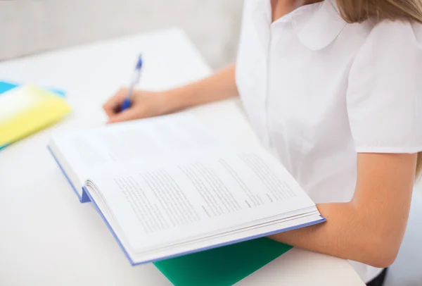 Student tjej skriver i anteckningsboken i skolan — Stockfoto