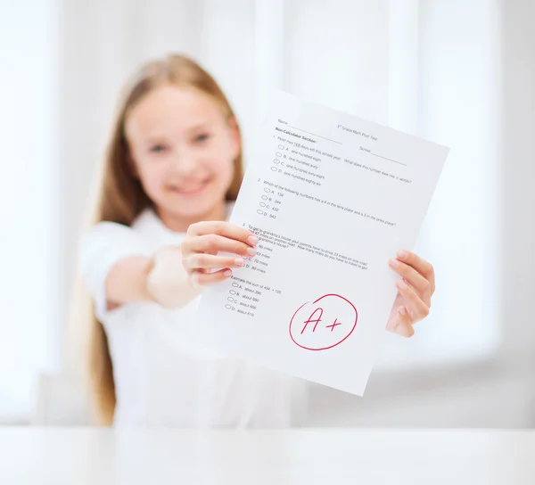 Smiling little student girl with test and A grade