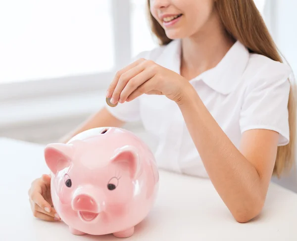 Criança sorrindo colocando moeda em um grande banco porquinho — Fotografia de Stock