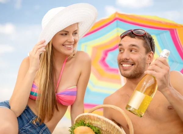 Leende par ha picknick på stranden — Stockfoto