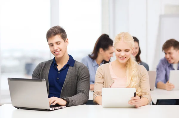 Due studenti sorridenti con laptop e tablet pc — Foto Stock