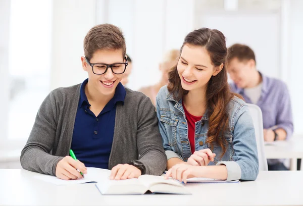 Twee tieners met notebooks en boek op school — Stockfoto