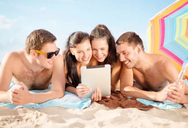 Groep lachende mensen met tablet pc op strand — Stockfoto