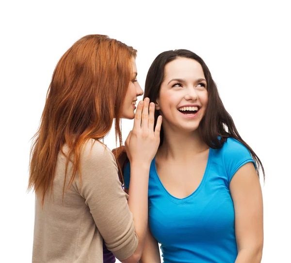 Deux filles souriantes chuchotant commérages — Photo