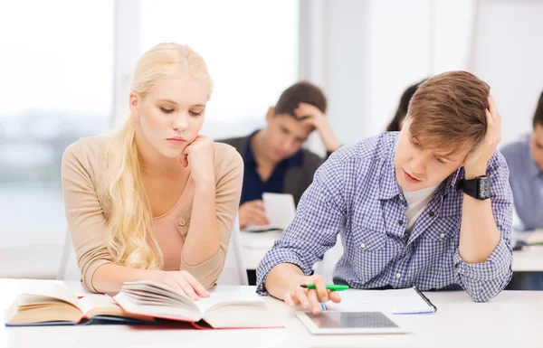 Estudiantes cansados con tablet pc, libros y cuadernos — Foto de Stock