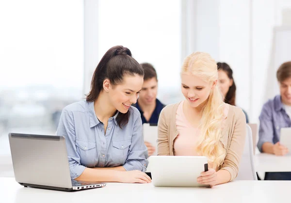 Два улыбающихся студента с ноутбуком и планшетным ПК — стоковое фото