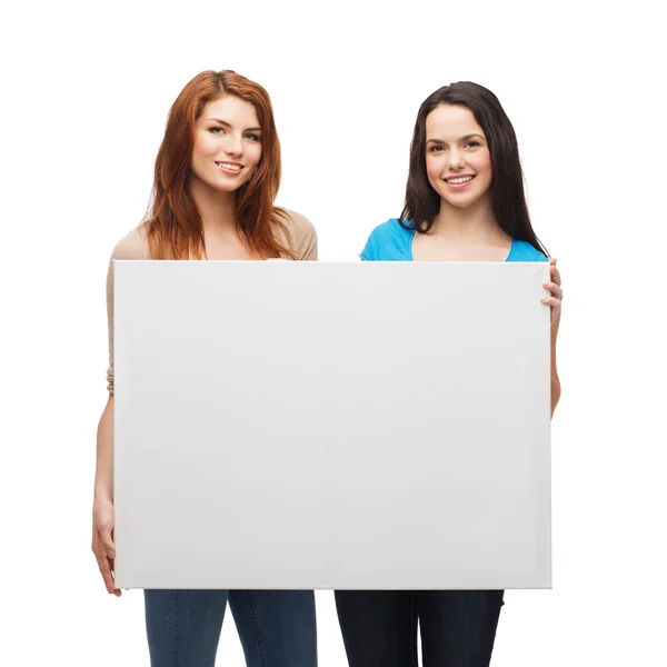 Two smiling young girls with blank white board Royalty Free Stock Images