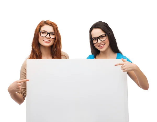 Two smiling girls with eyeglasses and blank board Stock Image