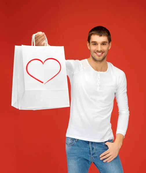 Hombre sonriente con bolsas de compras y el corazón en él — Foto de Stock