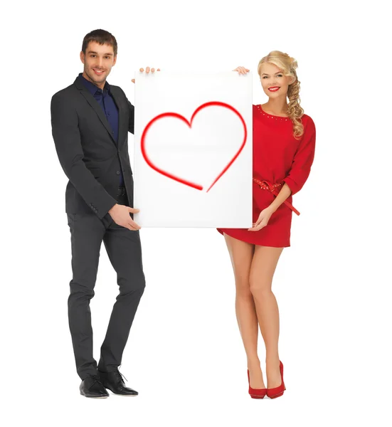 Smiling couple holding big white board with heart — Stock Photo, Image
