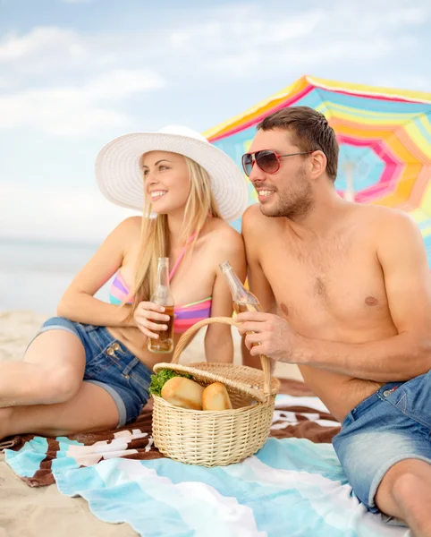 Lachende paar met picknick op het strand — Stockfoto