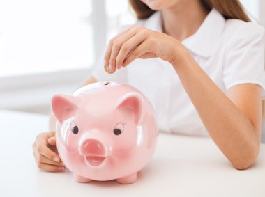 Smiling child putting coin into big piggy bank clipart