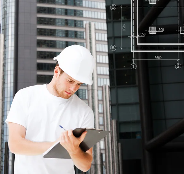 Male architect in helmet looking at blueprint — Stock Photo, Image