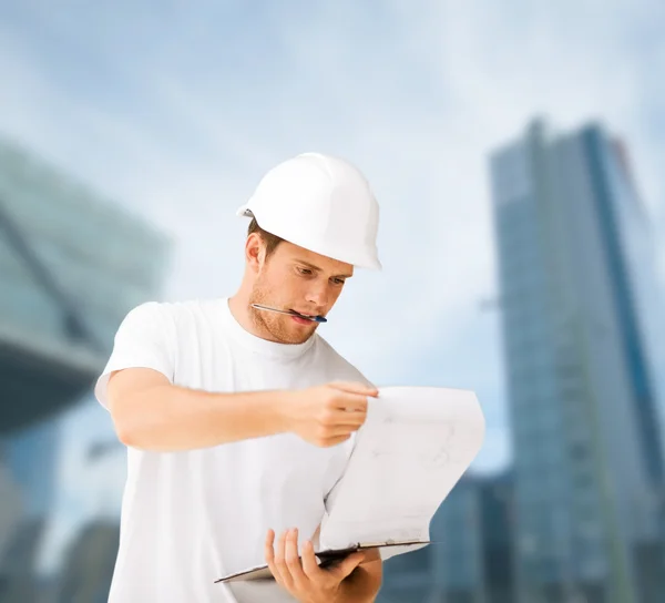 Male architect in helmet looking at blueprint — Stock Photo, Image