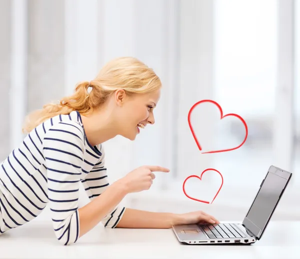 Smiling student girl pointing her finger at laptop — Stock Photo, Image