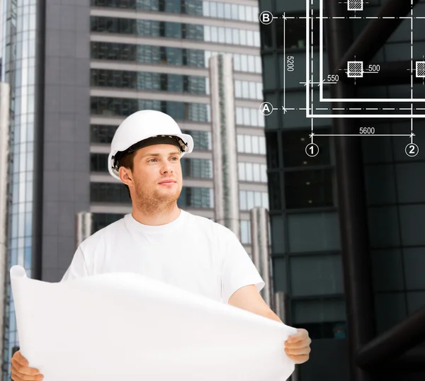 Male architect in helmet looking at blueprint — Stock Photo, Image