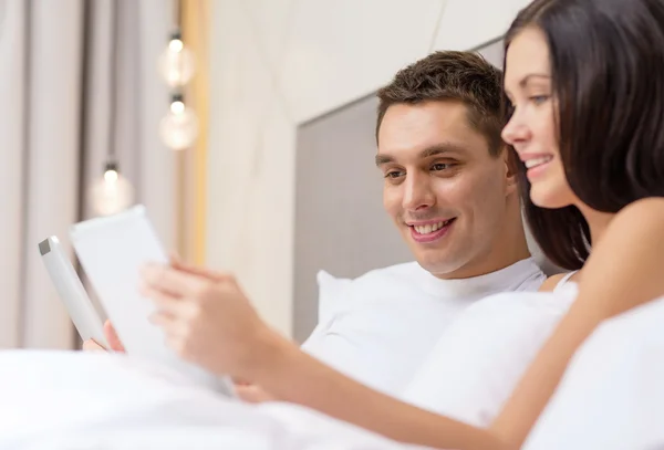 Pareja sonriente en la cama con tabletas PC — Foto de Stock