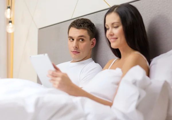 Sorrindo casal na cama com computadores tablet pc — Fotografia de Stock