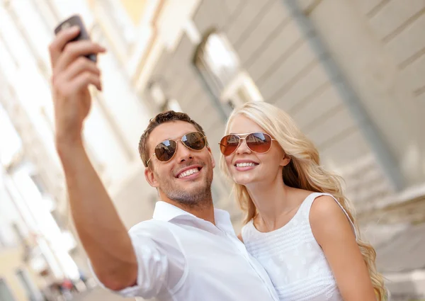 Lachende paar met smartphone in de stad — Stockfoto