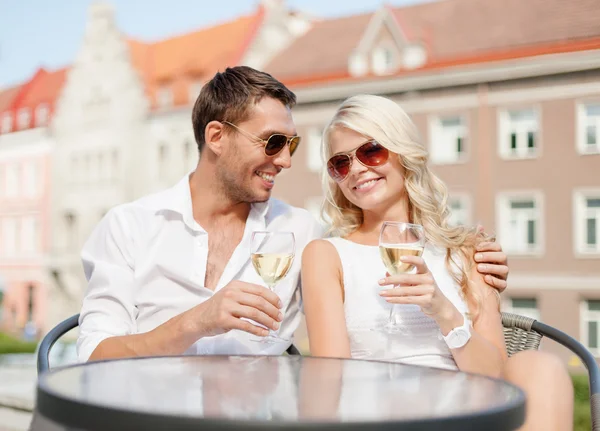 Lächelndes Paar mit Sonnenbrille trinkt Wein im Café lizenzfreie Stockfotos