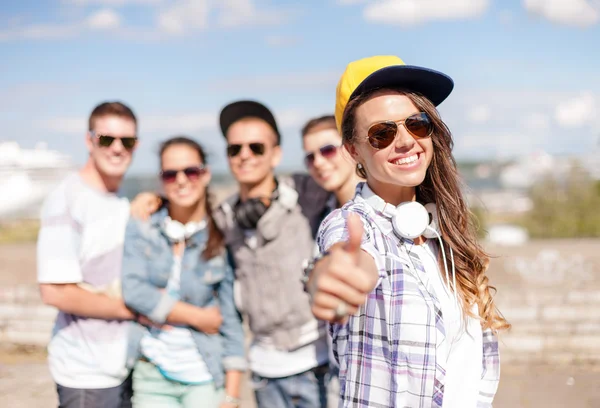 Tienermeisje met hoofdtelefoons en vrienden buiten — Stockfoto