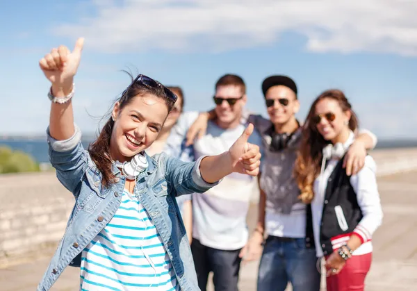 Tienermeisje met hoofdtelefoons en vrienden buiten — Stockfoto