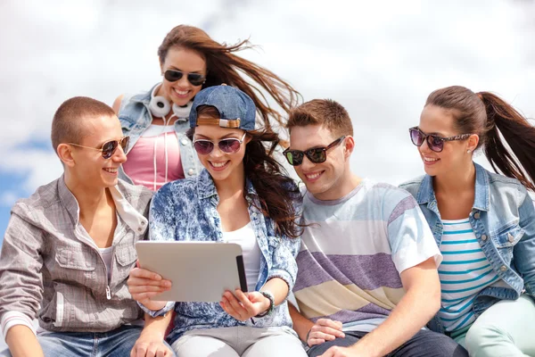 Groep van lachende tieners kijken naar tablet pc Stockfoto