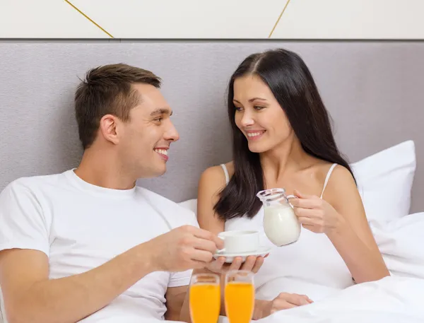 Pareja sonriente desayunando en la cama en el hotel — Foto de Stock