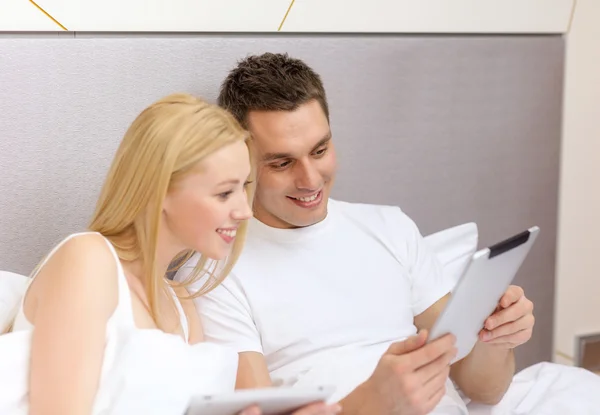 Lachende paar in bed met tablet pc-computers — Stockfoto