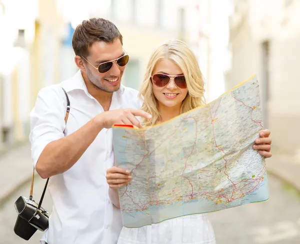 Lachende paar in zonnebril met kaart in de stad — Stockfoto