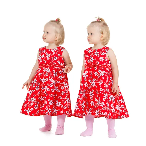 Two identical twin girls in red dresses looking — Stock Photo, Image