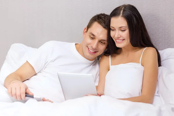 Smiling couple in bed with tablet pc computers — Stock Photo, Image