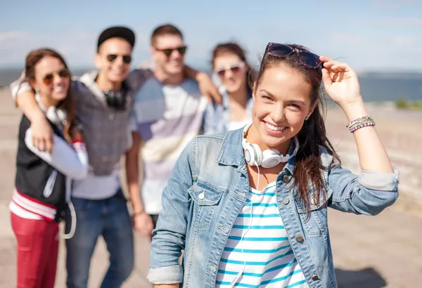 Kulaklıklar ve arkadaşlarıyla dışarıda genç kız — Stok fotoğraf