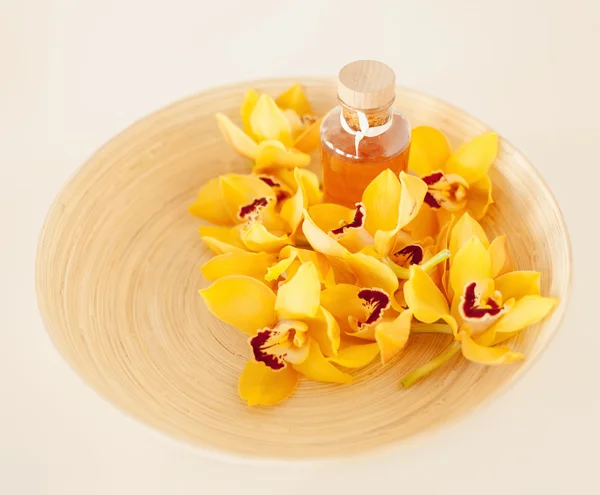 Closeup of wooden bowl with orchids and oil — Stock Photo, Image