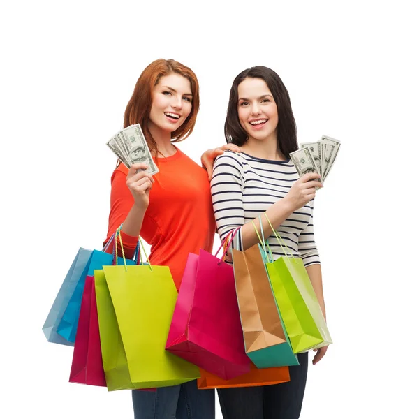 Lachende tienermeisjes met shopping tassen en geld — Stockfoto