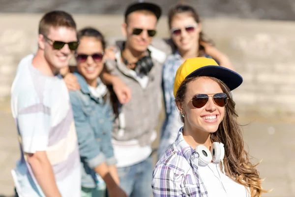 Ragazza adolescente con cuffie e amici al di fuori — Foto Stock