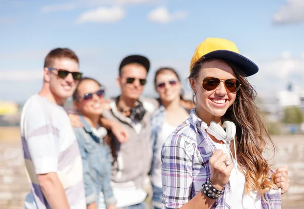 Adolescente chica con auriculares y amigos fuera — Foto de Stock