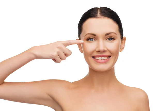 Young calm woman pointing to her eye — Stock Photo, Image