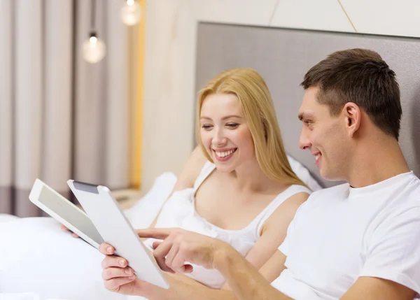 Lachende paar in bed met tablet pc-computers — Stockfoto