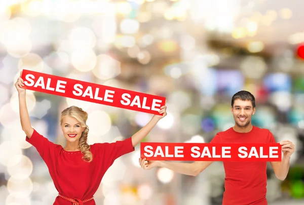 Mujer sonriente y hombre con letreros rojos de venta —  Fotos de Stock