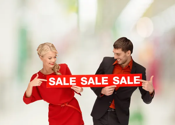 Woman and man pointing finger to red sale sign — Stock Photo, Image