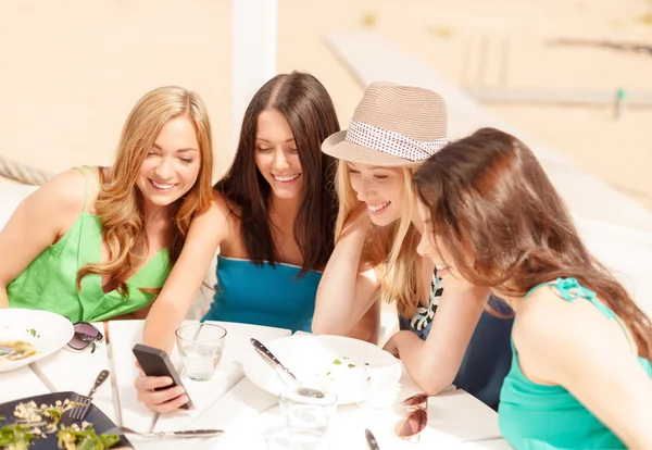 Meisjes op zoek naar smartphone in café op het strand — Stockfoto