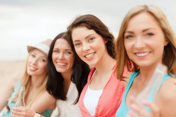 Smiling girls with drinks on the beach — Stock Photo, Image