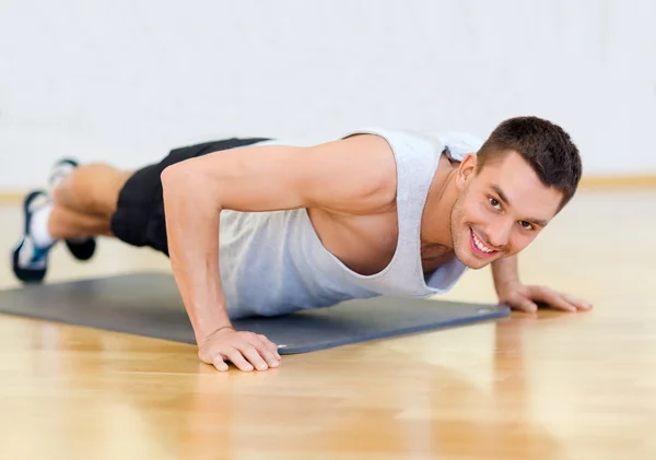 做俯卧撑在健身房里的男人微笑着 — 图库照片