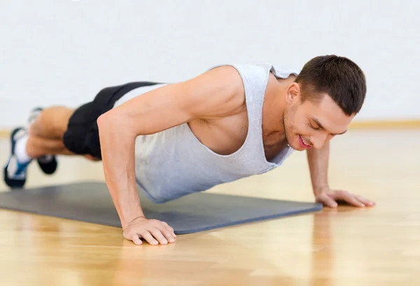 Χαμογελαστός άνθρωπος κάνει push-ups στο γυμναστήριο — Zdjęcie stockowe